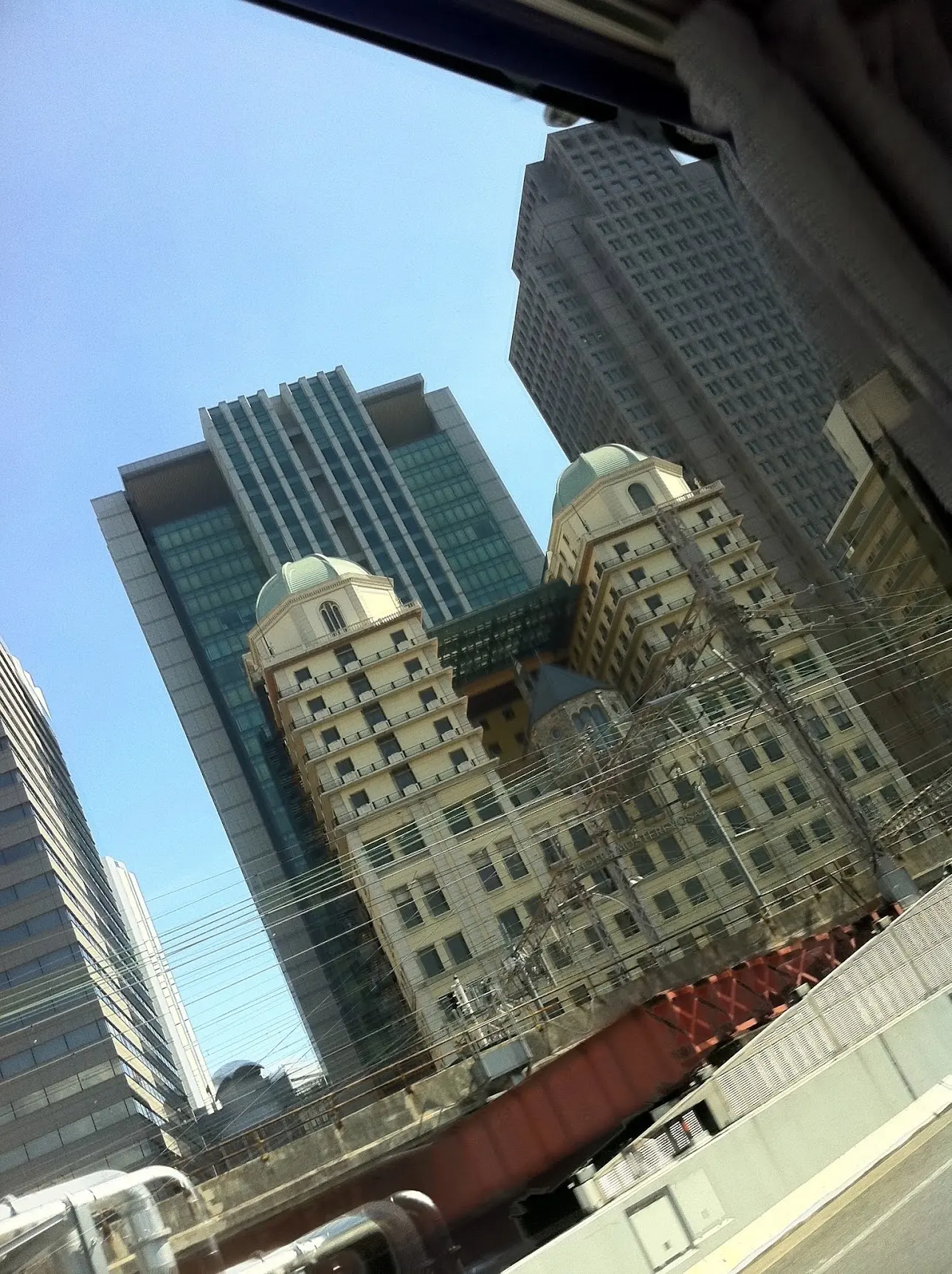 Looking up past railway wires at towers and a building with two green domes