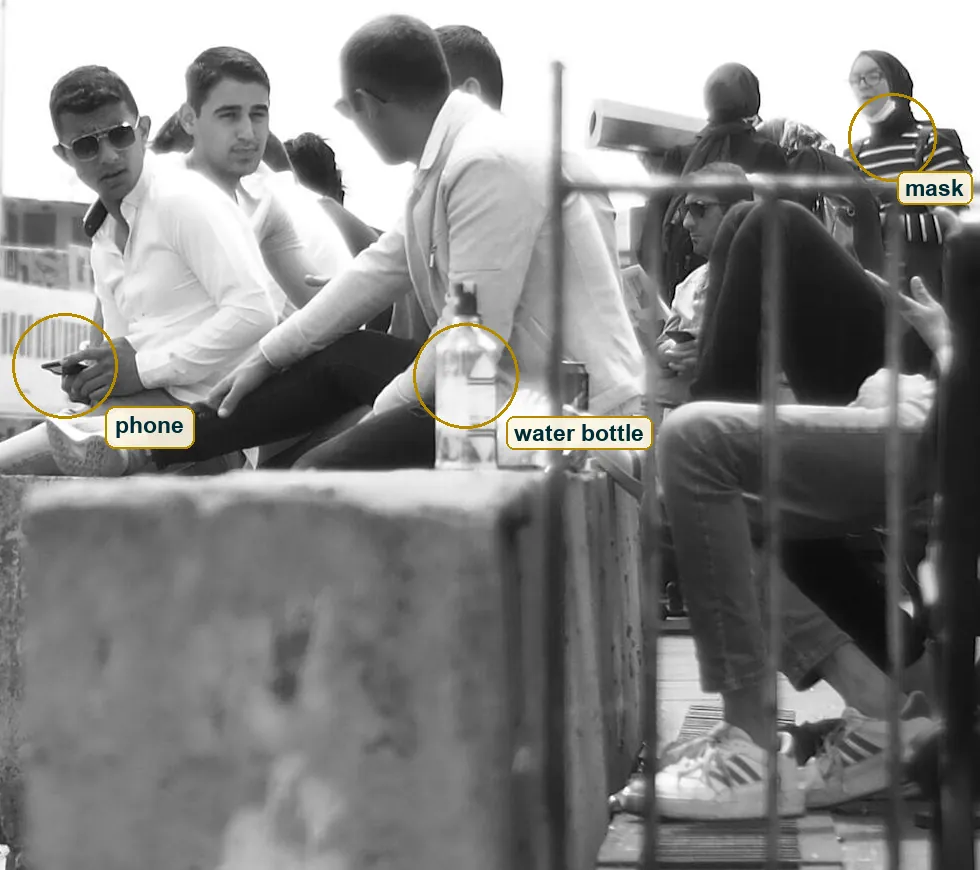 Right part of the photo with the people on the wall, a water bottle and a pulled down mask marked