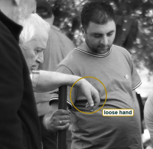 Crop of an older man's forearm draped over the pole, the hand hanging loose beside the young man