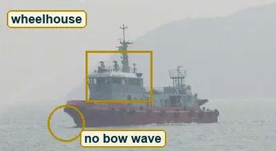 Close crop of the red-hulled ship with white superstructure and calm water at its bow
