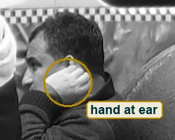 Crop of the seated man in a knit sweater pressing his hand to his ear