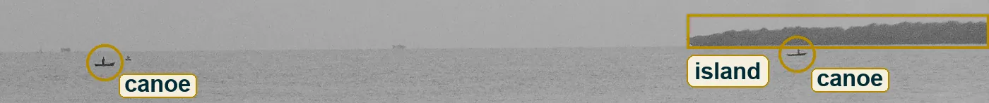 Crop of the far water with two small canoes and the low island on the right