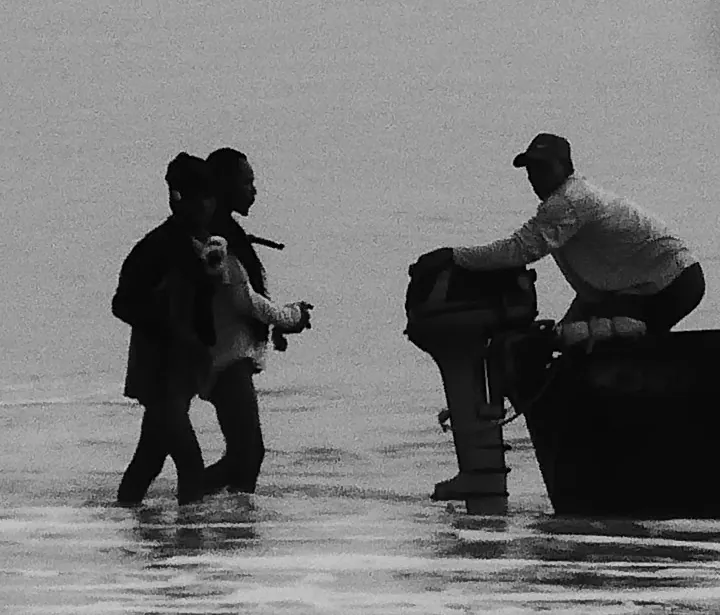 Crop of the two people wading at the stern beside the outboard motor